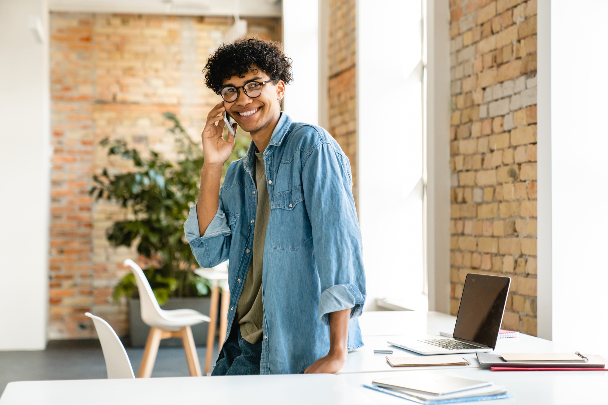 cheerful young african businessman talking on phone in the office.jpg